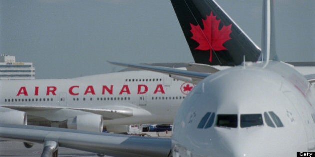 Pics of travellers in line at Air Canada deaparture area,travellers and people looking at departure board with Air Canada and travellers in line in backround.Pics of flight attendants walking by Air Canada signage also silohuette of cflight attendant with Air Canada signage in foreground.Jim Sprott in line going to Calgary for vacation.Alex Gann with son Matthew Gann,4,in line going home to Edmonton.Pics of Air Canada depot with planes about to land with planes on ground that are at a stand still. (Photo by Vince Talotta/Toronto Star via Getty Images)