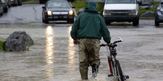 CANMORE, CANADA - JUNE 21: A man pushes his bicycle through the floodwater June 21, 2013 in Canmore, Alberta, Canada. Widespread flooding caused by torrential rains washed out bridges and roads prompting the evacuation of thousnds. (Photo by John Gibson/Getty Images)