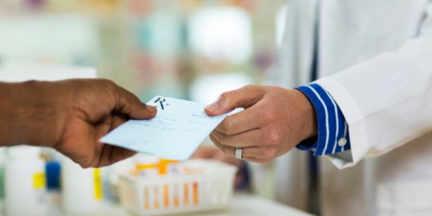 A man handing a prescription to a pharmacists