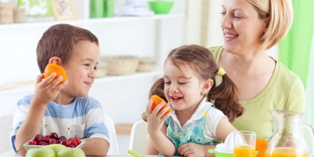 Mother and children cutting fruit in the kitchen