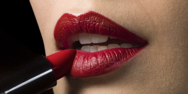 Female applying red lipstick, close up