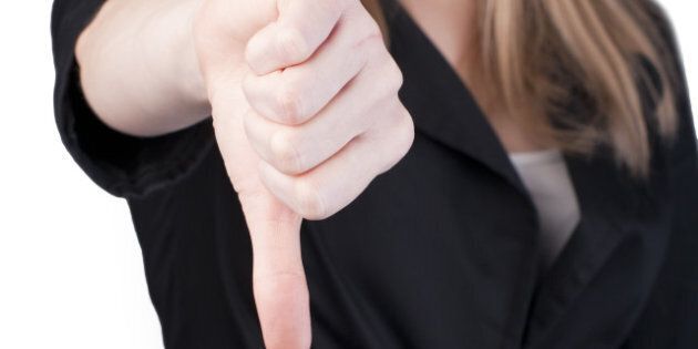 Attractive blonde woman in professional business suit pointing her thumbs down