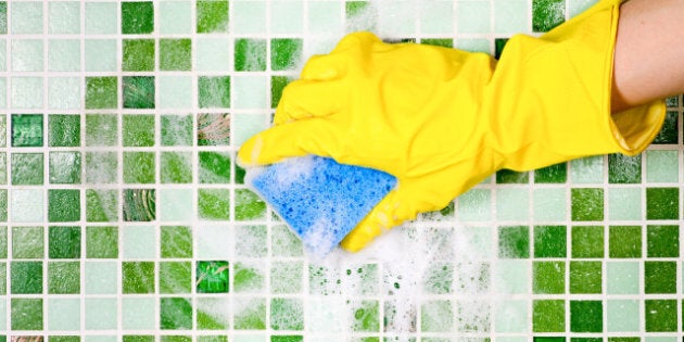 Hand in yellow protective glove cleaning mosaic wall