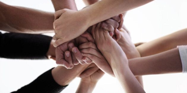 A low angle cropped shot of a group of people holding hands together during a support group session