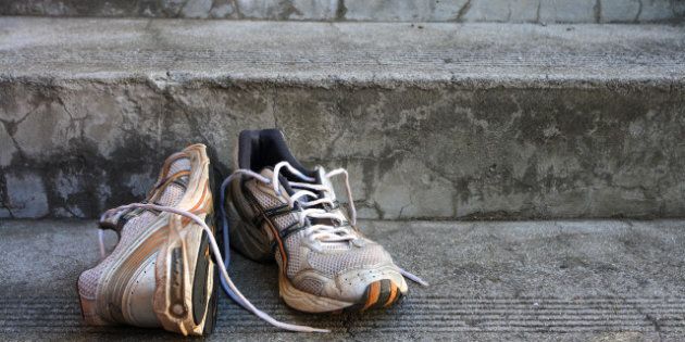 A pair of old used running shoes on cement steps.