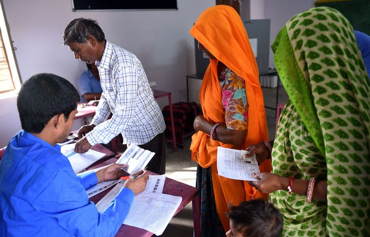 Voters check their name before casting their vote during general election in village Kapoorawala, in Sanganer on the outskirts of Jaipur on May 6, 2019. 
