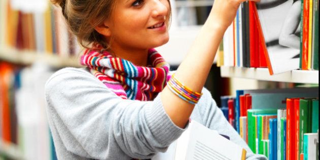 Female student selecting book from library shelf