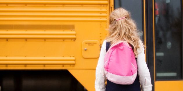 Elementary girl with a back pack heading toward the school bus.