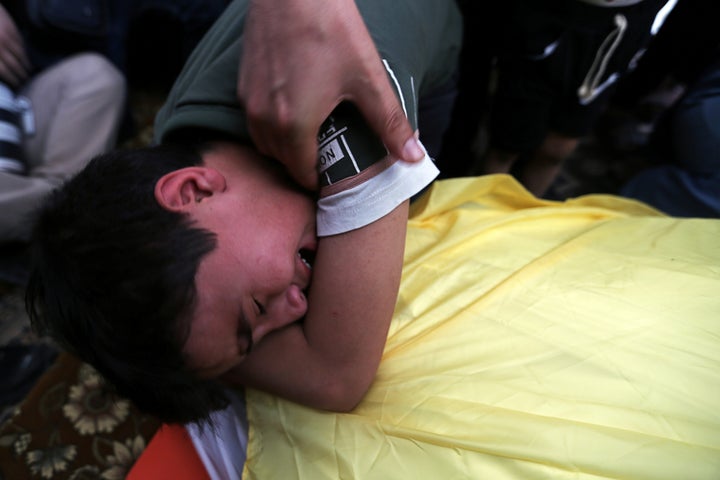 The son of Palestinian Hani Abu Sha'ar, who was killed in an Israeli air strike, mourns over his father's body during his fun