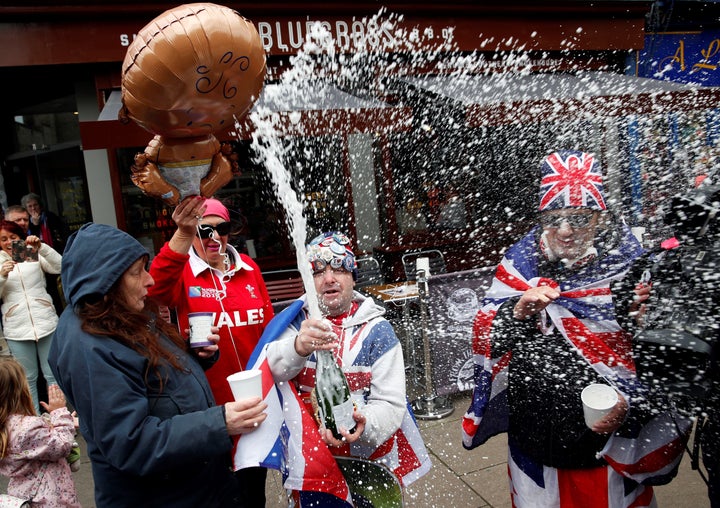 Royal super fans John Loughery (C) pops the cork on a bottle of Champagne, as they stand near Windsor Castle on Monday, following the announcement that Meghan, Duchess of Sussex, has given birth to a son.