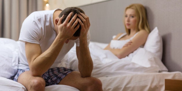 hotel, travel, relationships, and sexual problems concept - upset man sitting on the bed with woman on the back