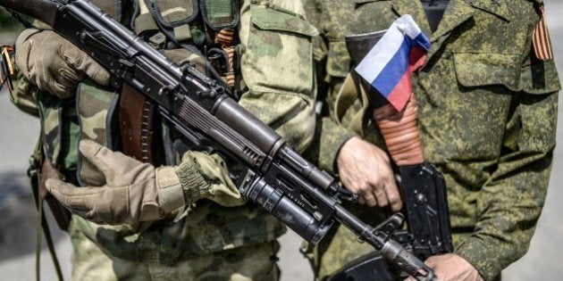 A pro-Russia separatist with a Russian national flag attached on his uniform, stands next a comrade, at a checkpoint near the front line in the northern outskirts of city of Donetsk, on July 22, 2014. Terrified civilians fled as intense clashes yesterday between Ukrainian government troops and pro-Russian rebels left at least four people dead on the outskirts of the insurgent bastion of Donetsk. A military spokesman said yesterday government troops were battling back control of the districts around the airport and had broken through the rebel cordon to reach their comrades inside. AFP PHOTO/ BULENT KILIC (Photo credit should read BULENT KILIC/AFP/Getty Images)