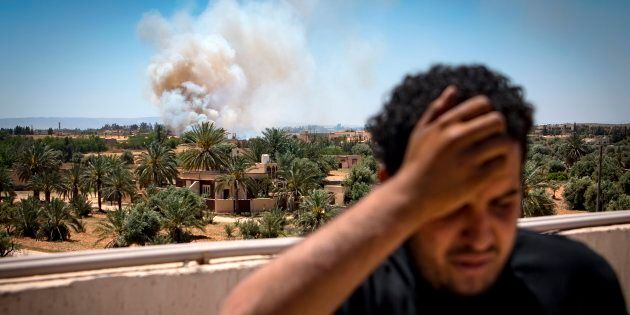 Un combattant fidèle au gouvernement du GNA, internationalement reconnu, se dresse sur un toit alors que la fumée monte au loin à la suite d'un d'affrontements avec les forces loyales à l'homme fort Khalifa Haftar, à Espiaa, à environ 40 kilomètres au sud de la capitale libyenne.