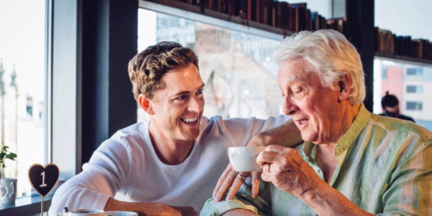 Mature father and son enjoying a coffee together, the son looks proud of his dad and they are chatting happily together.