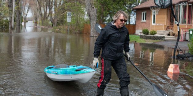 A man walks while pulling his canoe on the flooded streets in Pierrefonds on Sunday May 7, 2017. More than 130 communities in the province have been hit by the flooding, with an estimated 1,500 homes affected and 850 people forced to evacuate. / AFP PHOTO / Catherine Legault (Photo credit should read CATHERINE LEGAULT/AFP/Getty Images)