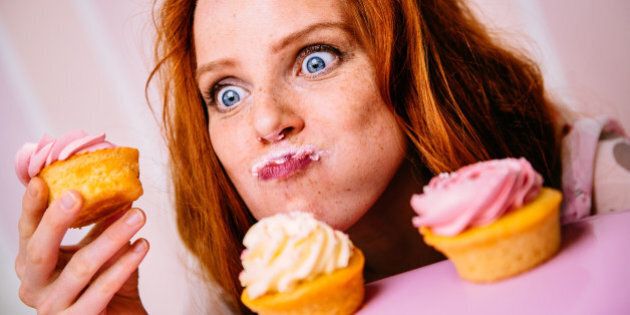 Young red head woman is enjoying cupcakes with a lot of enthusiasm