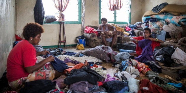 Fijian 10-year-old Lusiana (R) helps her grandmother (C) and aunt (L) sort through clothes in Rakiraki...