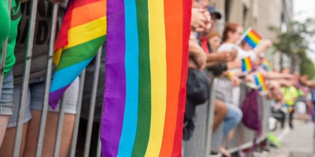 Gay rainbow flags at Montreal gay pride parade with blurred spectators in the background