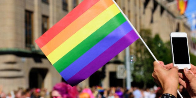 Pride flag and spectator taking pictures with mobile phone