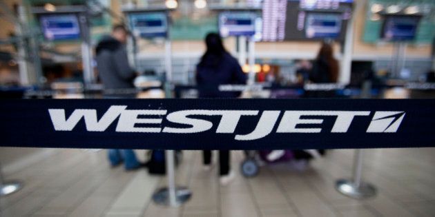 Westjet Airlines Ltd. signage is displayed on a band as travelers stand in line at Vancouver International Airport (YVR) in Richmond, British Columbia, Canada, on Wednesday, Nov. 13, 2013. The number of international visitors to Canada plunged 20 per cent since 2000 even as global travel soars, according to a sobering report being released Thursday by Deloitte Canada. Photographer: Ben Nelms/Bloomberg via Getty Images
