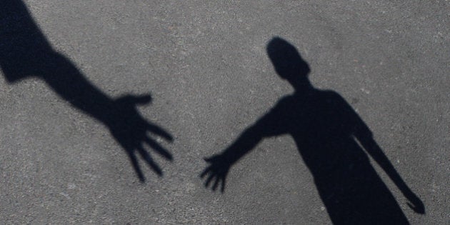 Helping Hand with a shadow on pavement of an adult hand offering help or therapy to a child in need as an education concept of charity towards needy kids and teacher guidance to students who need tutoring.