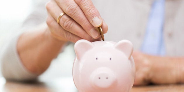 savings, money, annuity insurance, retirement and people concept - close up of senior woman hand putting coin into piggy bank