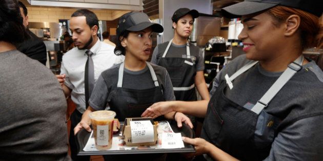 A preparer, center, hands off on order to a table server, right, in the kitchen of a McDonald's restaurant in New York's Tribeca neighborhood, Thursday, Nov. 17, 2016. On Thursday, the company said it wants to makes its fast-food outlets feel more like restaurants, with plans to eventually expand table service across its U.S. locations. (AP Photo/Richard Drew)