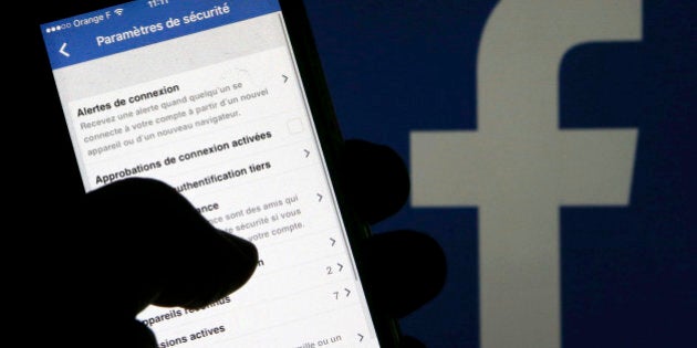 A man reads parameters of security on his phone in front of a displayed Facebook logo in Bordeaux, southwestern France, March 10, 2016. REUTERS/Regis Duvignau/Illustration