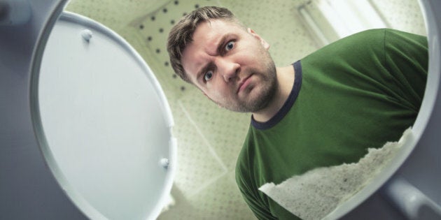 Man in the bathroom looking in the toilet bowl