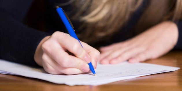 Close up of woman's hand writing on paper with a pen