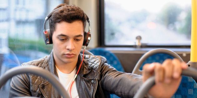 Mixed race man listening to headphones on bus