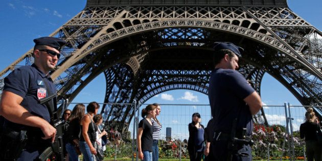 French CRS policemen patrol as tourists walk past in front of the Eiffel Tower in Paris, France August 20, 2016. REUTERS/Pascal Rossignol