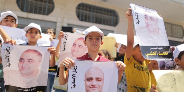 Palestinian demonstrators take part in a protest in solidarity with Mohammad El Halabi, World Vision's manager of operations in Gaza who was accused by Israel of funnelling millions of dollars in aid money to Hamas, organised by foundations and societies benefiting from World Vision in Gaza City August 7, 2016. (Photo by Momen Faiz/NurPhoto via Getty Images)