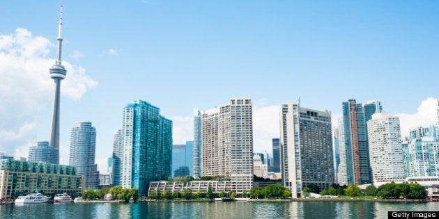 The Toronto waterfront on a sunny summer day from Lake Ontario with reflections of the buildings in the water.