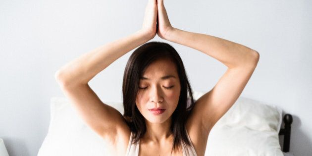 asian woman doing yoga in the bedroom
