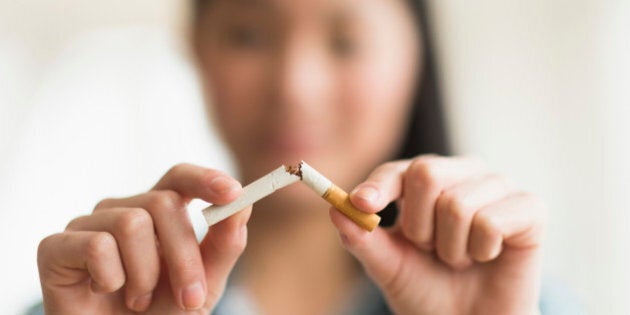 Mixed race teenage girl breaking cigarette in half