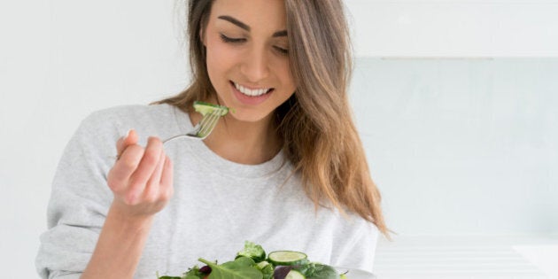 Healthy young woman dieting and eating a salad at home