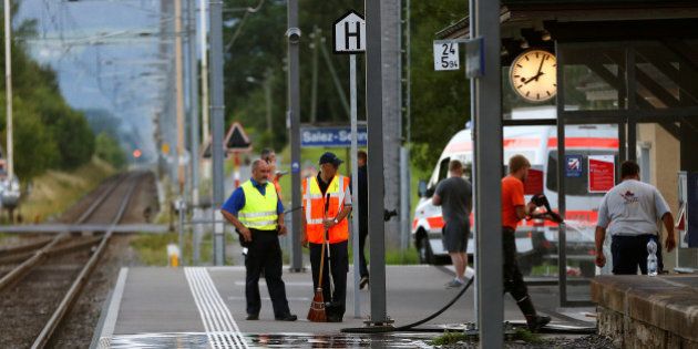 A Swiss police officer stands near workers cleaning a platform after a 27-year-old Swiss man's attack on a Swiss train at the railway station in the town of Salez, Switzerland August 13, 2016. REUTERS/Arnd Wiegmann TPX IMAGES OF THE DAY