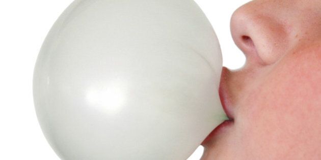 Close-up of a young boy making a bubble with his gum, isoated on white.