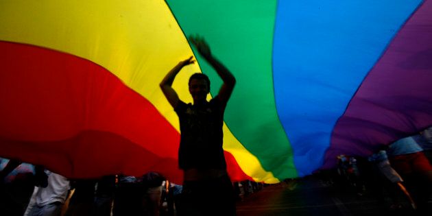 A gay rights activist dances under a rainbow flag during the Gay Pride parade in downtown Athens, on Saturday, June 4, 2011. Around 2000 people took part in the march. (AP Photo/Kostas Tsironis)