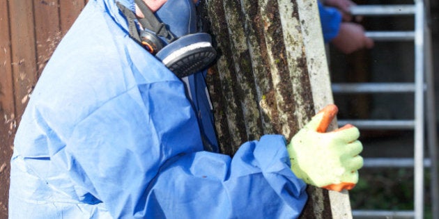 Asbestos corrugated roofing sheet being removed and sealed in a plastic sheet