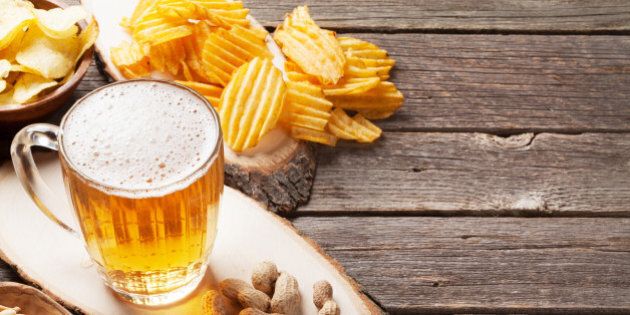 Lager beer mug and snacks on wooden table. Nuts, chips. With copy space