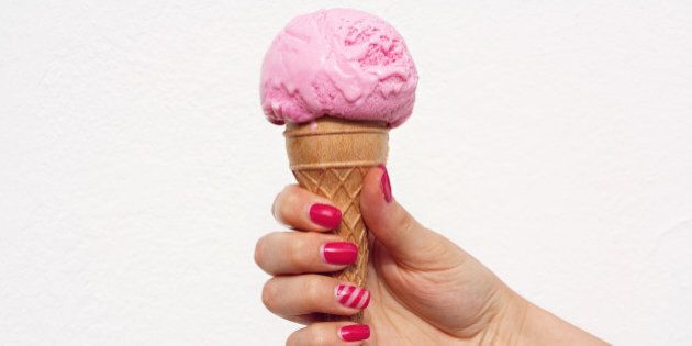 Girl hold strawberry ice cream cone in hand with beautiful manicure