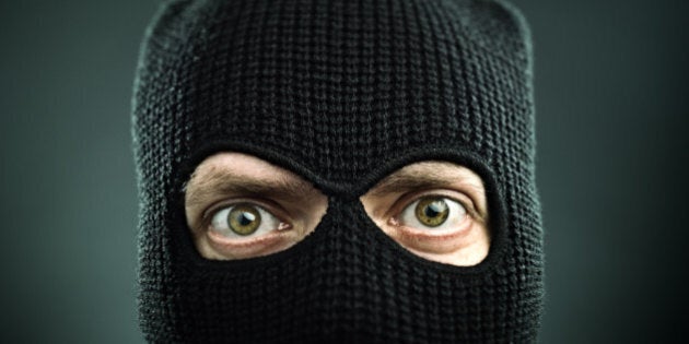 Man with a balaclava looking at camera. Black background.