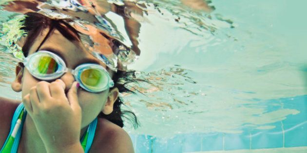 Little girl swimming underwater wearing goggles.