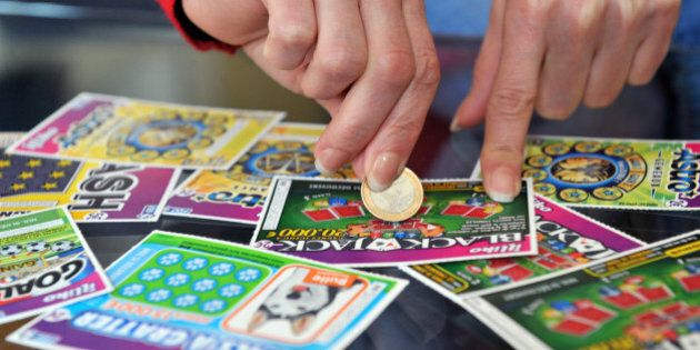 A player scratches a game card of the FranÃ§aise des Jeux (FDJ), the operator of France's national lottery, on May 28, 2013 in Nantes. AFP PHOTO / FRANK PERRY (Photo credit should read FRANK PERRY/AFP/Getty Images)