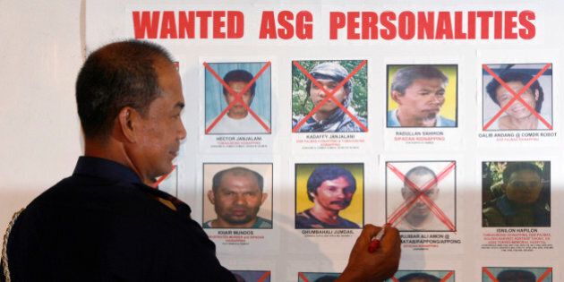 Philippine police chief Director General Jesus Verzosa crosses out the picture of Mujibar Alih Amon, an alleged member of Abu Sayyaf, from a roster of wanted persons during a news conference in main police headquarters Camp Crame in Manila's suburban Quezon city February 25, 2010. Verzosa announced on Thursday the arrest of Amon who was allegedly involved in the kidnapping of 19 foreigners in Sipadan, Malaysia and the abduction of American Jeffrey Schilling in 2000. REUTERS/Erik de Castro (PHILIPPINES - Tags: CRIME LAW POLITICS)