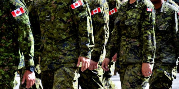 A group of Canadian soldiers wearing green camouflage uniforms march together.