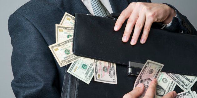 Businessman with a briefcase full of money in the hands of on gray background