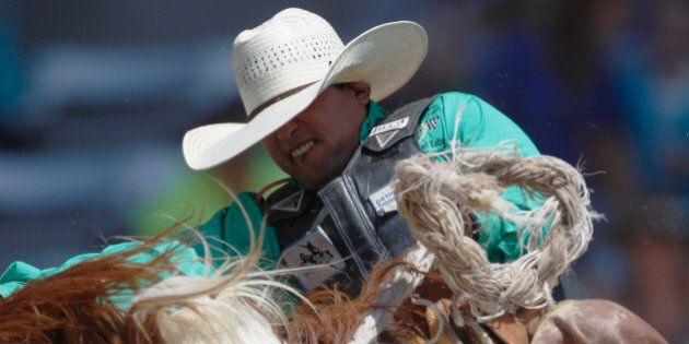 CHEYENNE, WY - JULY 23: Saddle bronc rider Joaquin Real is seen riding Swine Flu during a 76 point ride at the 117th annual Frontier Days rodeo and western celebration on July 23, 2013 in Cheyenne, Wyoming. (Photo by William Mancebo/Getty Images)